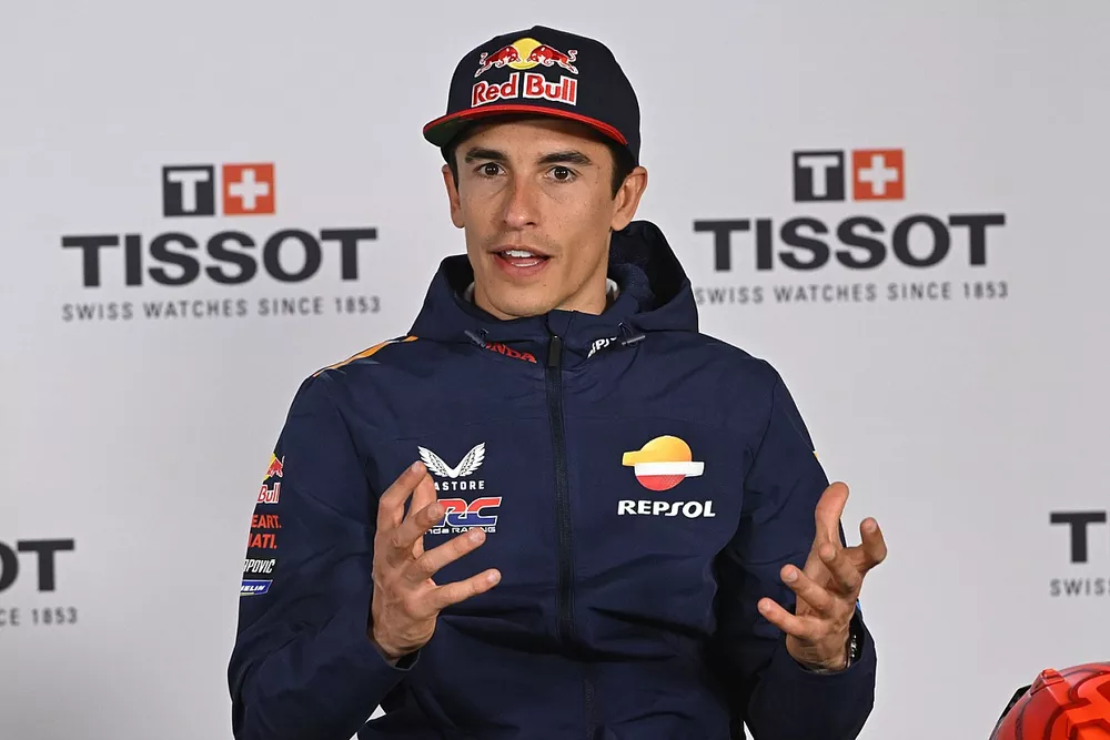 Marc Márquez en una pose victoriosa, celebrando su triunfo en la pista de MotoGP.